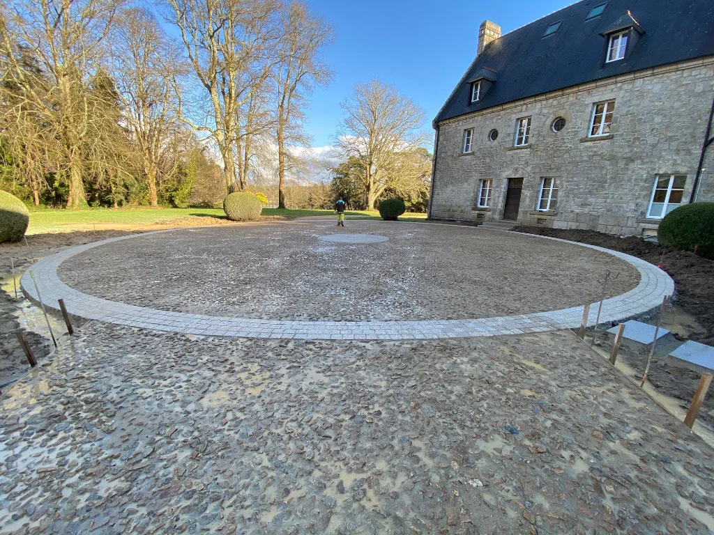 Un patio circulaire en pierre devant une maison.