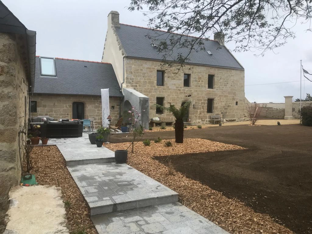 Une maison en pierre avec un jardin devant.